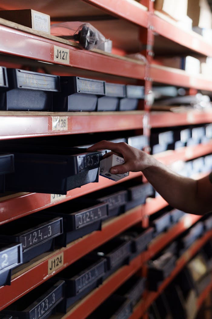 About Hand reaching for storage bin in organized warehouse shelving. Perfect for logistics and inventory themes.